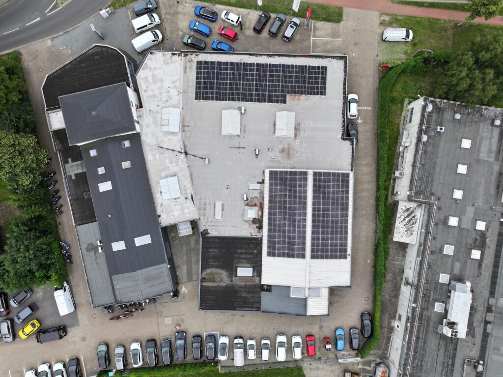 Drohnenaufnahme des Autohaus Hakelberg mit mehreren Gebäuden, Parkplätzen und großen Solaranlagen auf den Dächern.