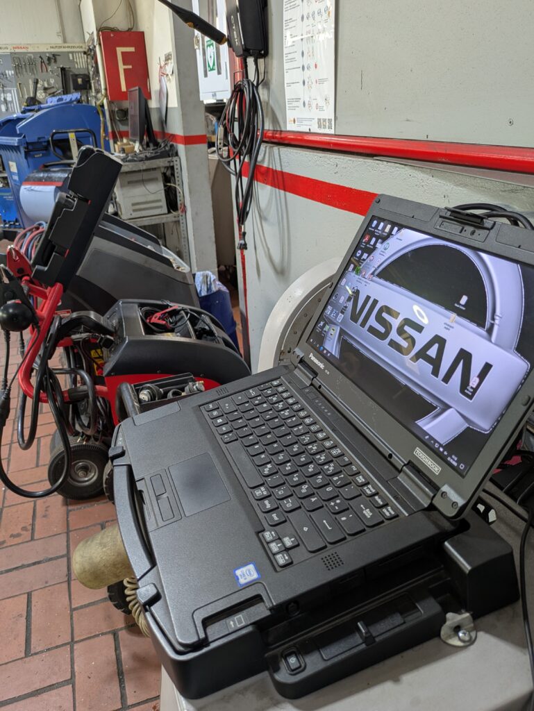 Werkstattbild mit verschiedenen Maschinen und einem Auslese Laptob mit Nissan Hintergrundbild