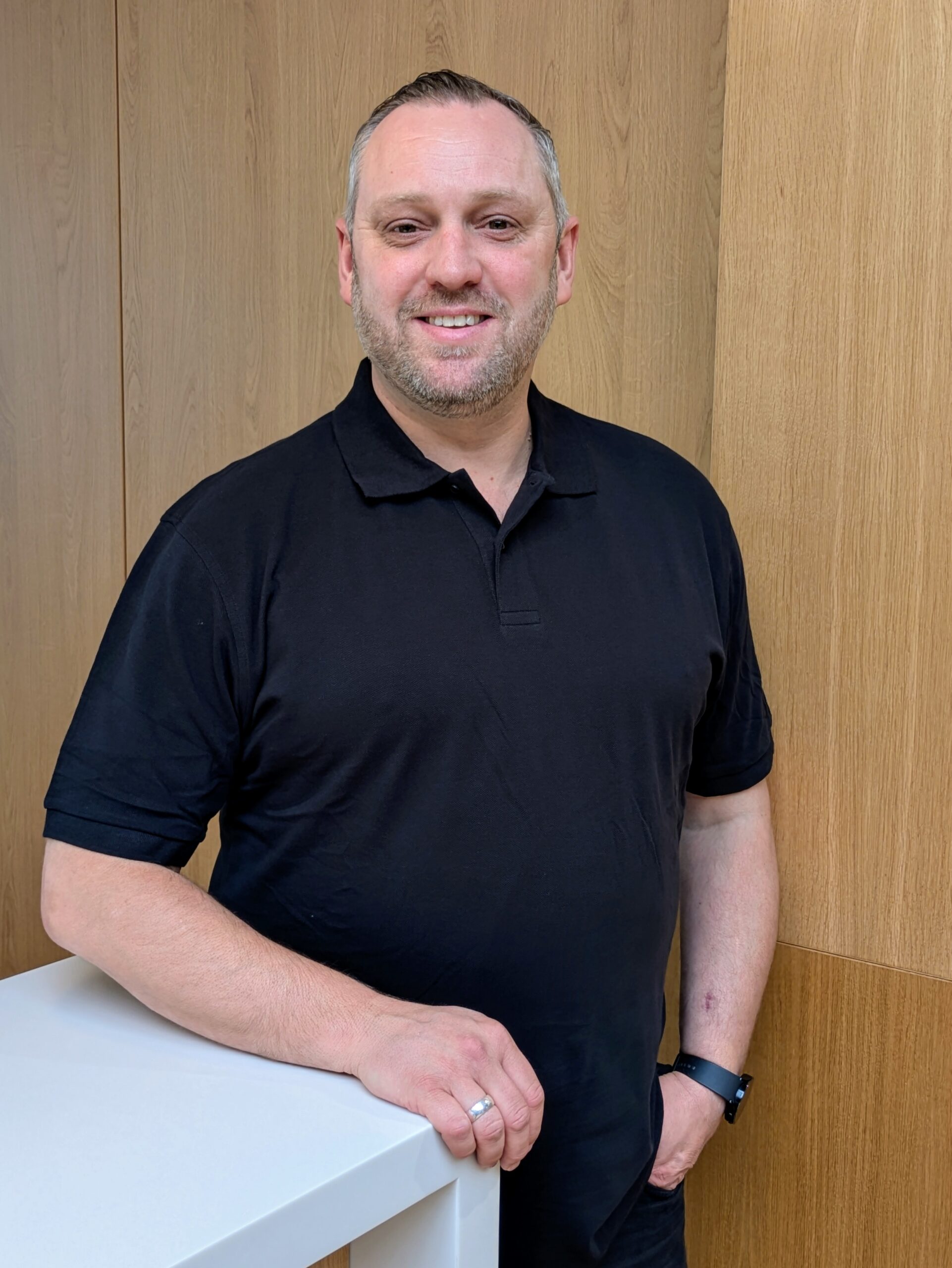 Eine Mitarbeiter an einen Verkaufstresen angelehnt lächlt in die Kamera