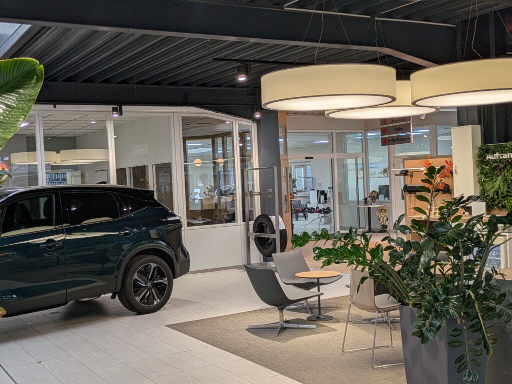 Wartebereich in der KIA Verkaufshalle mit Sitzmöglichkeiten und einem Dunklen KIA