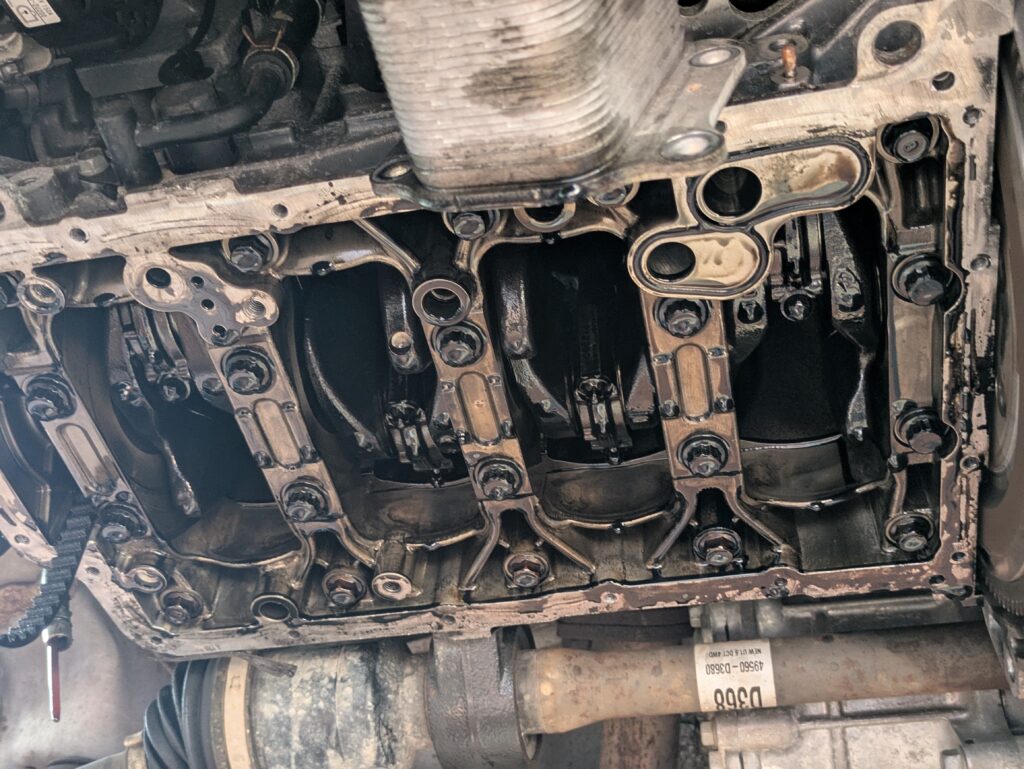 Geöffneter Motorblock mit sichtbaren Pleueln und Kurbelwelle bei einer Motorreparatur in der Werkstatt.